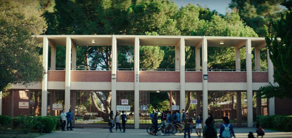 A group of people walking in front of a brick building. Description generated by AI
