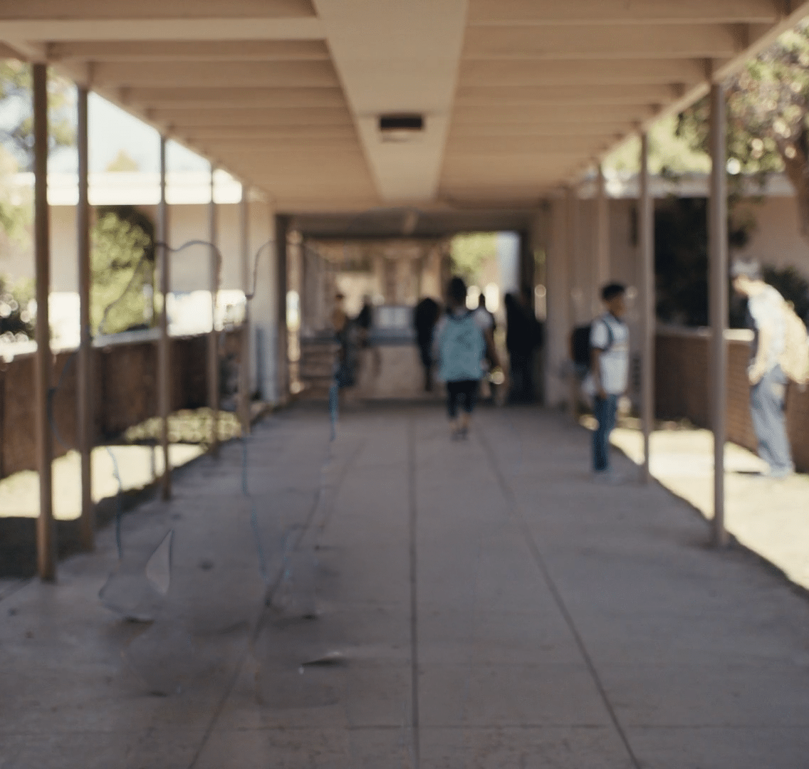 A hallway with a roof and people walking. Description generated by AI