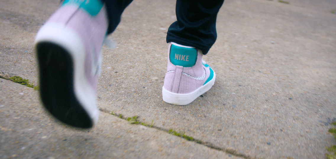 A person wearing a purple and blue Nike shoe. Description generated by AI