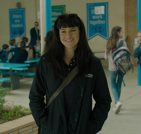 A woman wearing a black jacket and a brown purse. Description generated by AI