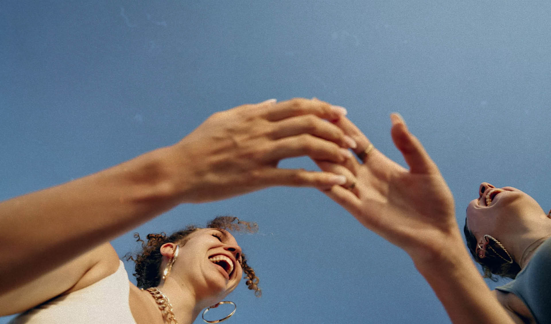 Two women with their hands in the air. Description generated by AI